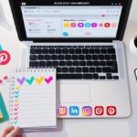 Flat-lay image of a digital workspace with a laptop, social media icons, checklist notepad, and smartphone analytics – representing a social media promotion strategy for blog posts.